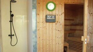 A wooden interior with a shower, a clock, and a sauna. - Accommodation with private terrace in tropical garden,  (Estepona)