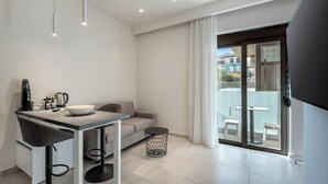 A modern kitchen with a dining area, a sofa, and a balcony with outdoor seating. - Harma City Living (Chania)