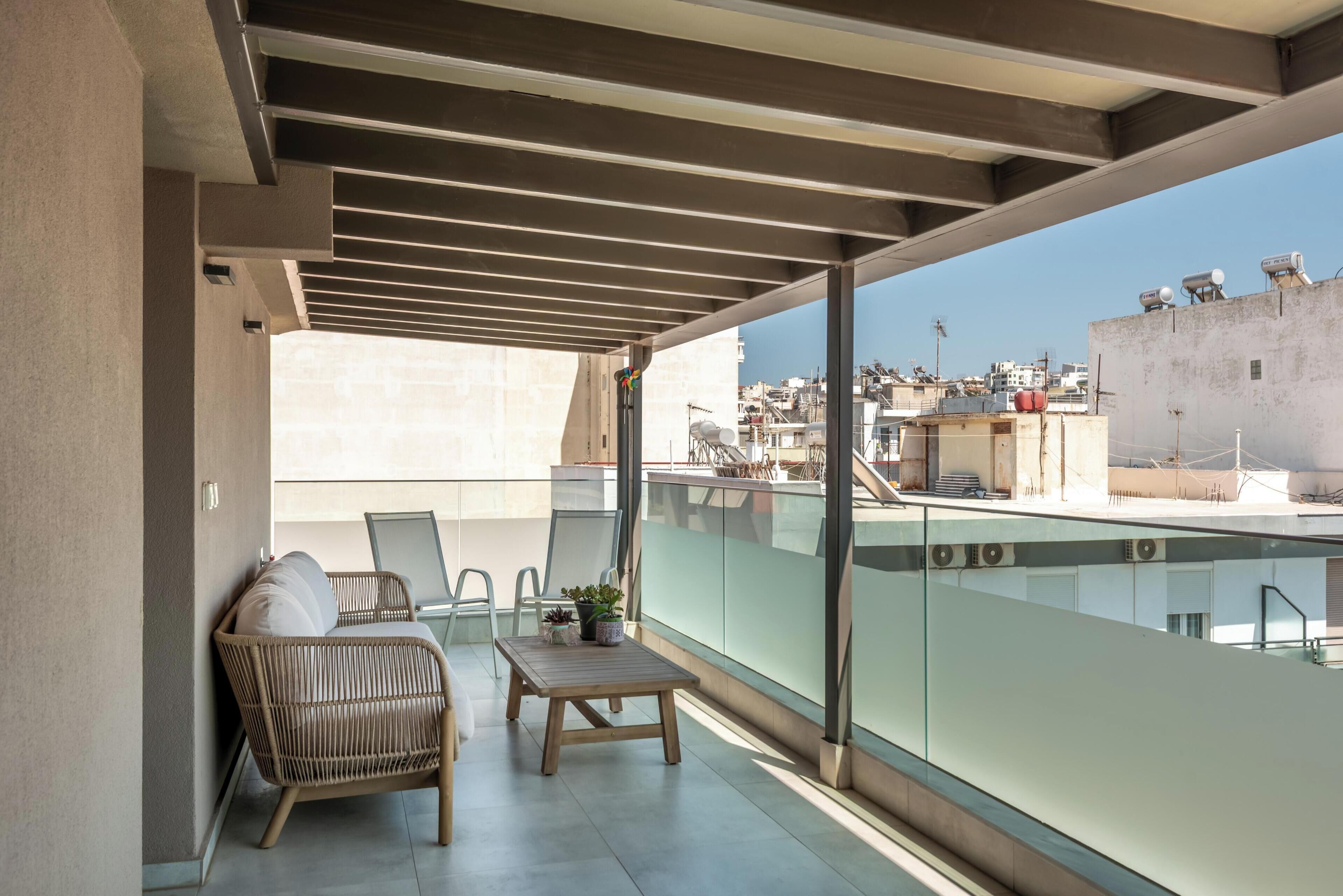 Ein Balkon mit Korbstuhl, kleinem Tisch und einer Topfpflanze.
