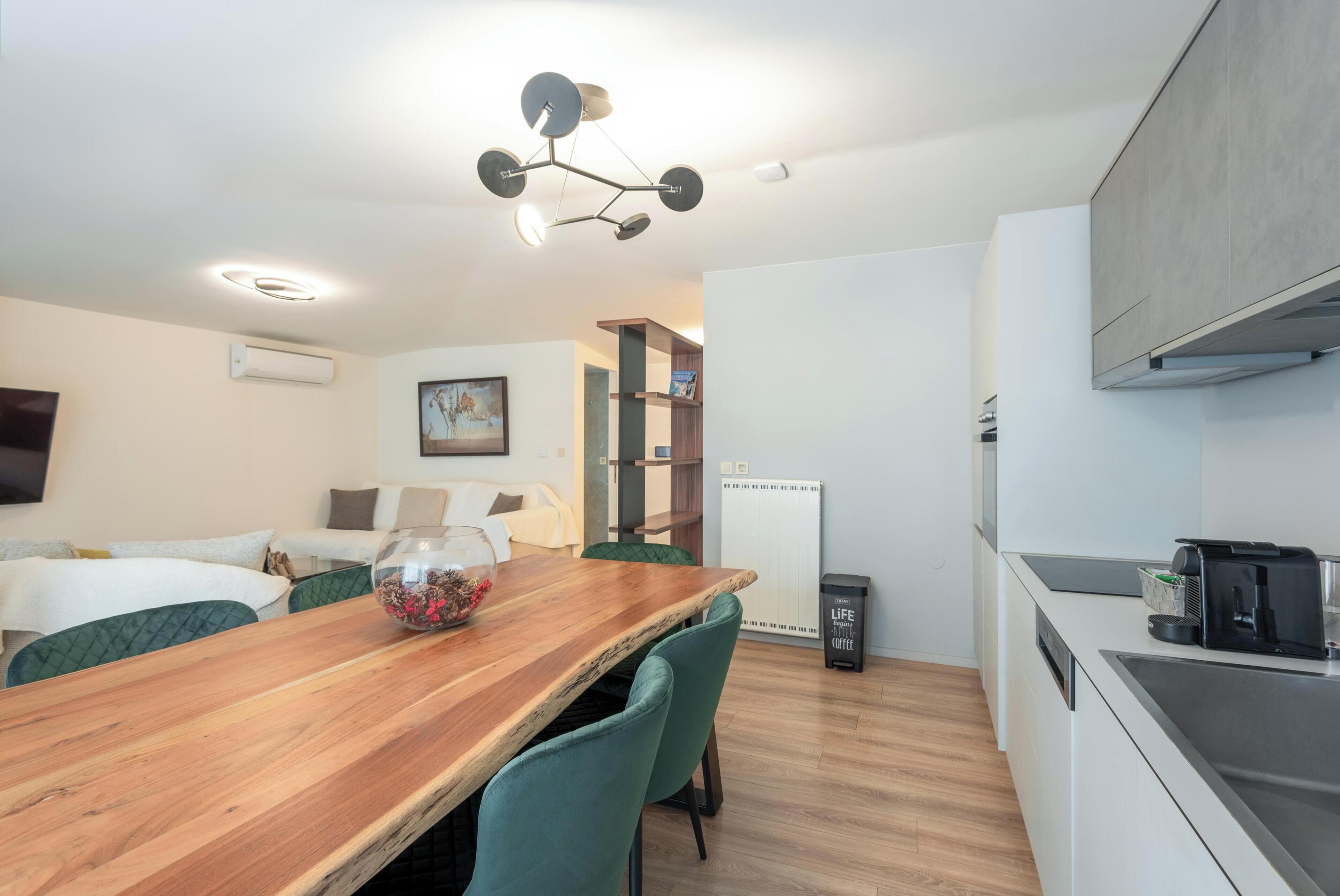 Una cocina moderna con una mesa de comedor de madera, una cafetera y un refrigerador.