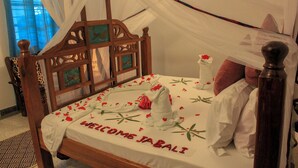 Un letto a baldacchino, una testiera in legno e una coperta con la scritta 'WELCOME JABALI'.