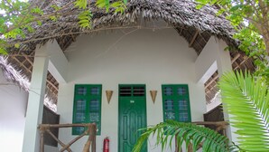 Un edificio con una porta verde, pareti bianche e un tetto di paglia.
