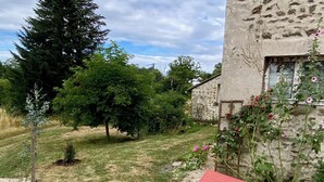 A garden with red lounge chairs, a stone wall, and a variety of trees and shrubs. - Spacious houses in Normandy, aux Alpes Mancelles (Moulins-le-Carbonnel)