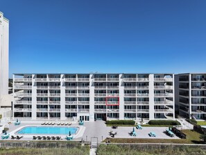 A multi-story hotel with a swimming pool and outdoor seating.