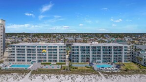 A modern hotel with multiple floors, a pool area, and a beach view.