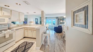 A modern kitchen with white cabinetry, a central island, and a view to a balcony.