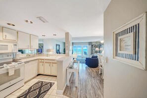 Una cocina moderna con armarios blancos, una isla central y vistas a un balcón.