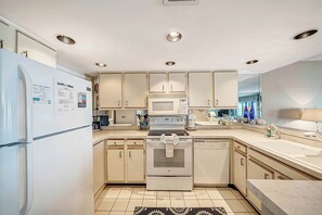 Una cocina moderna con armarios blancos, un refrigerador, un microondas, un horno y un lavavajillas.