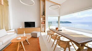 Ein modernes Wohnzimmer mit Fernseher, Holzmöbeln und einem großen Fenster mit Blick auf eine schöne Aussicht.