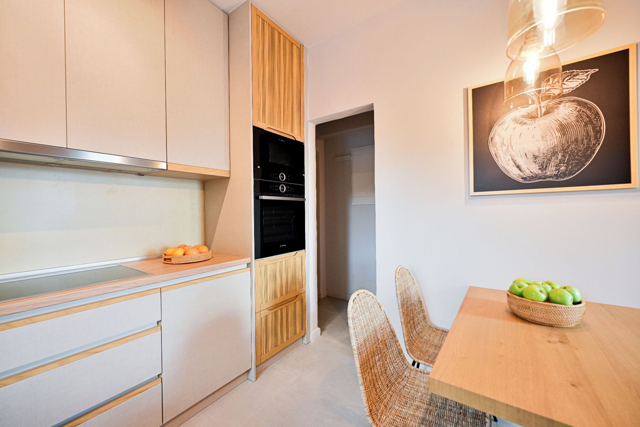 A modern kitchen with wooden cabinets, a built-in oven, and a dining area with a table and chairs.