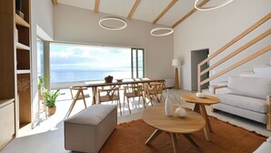 Ein modernes Wohnzimmer mit großem Fenster, Holzmöbeln und Meerblick.