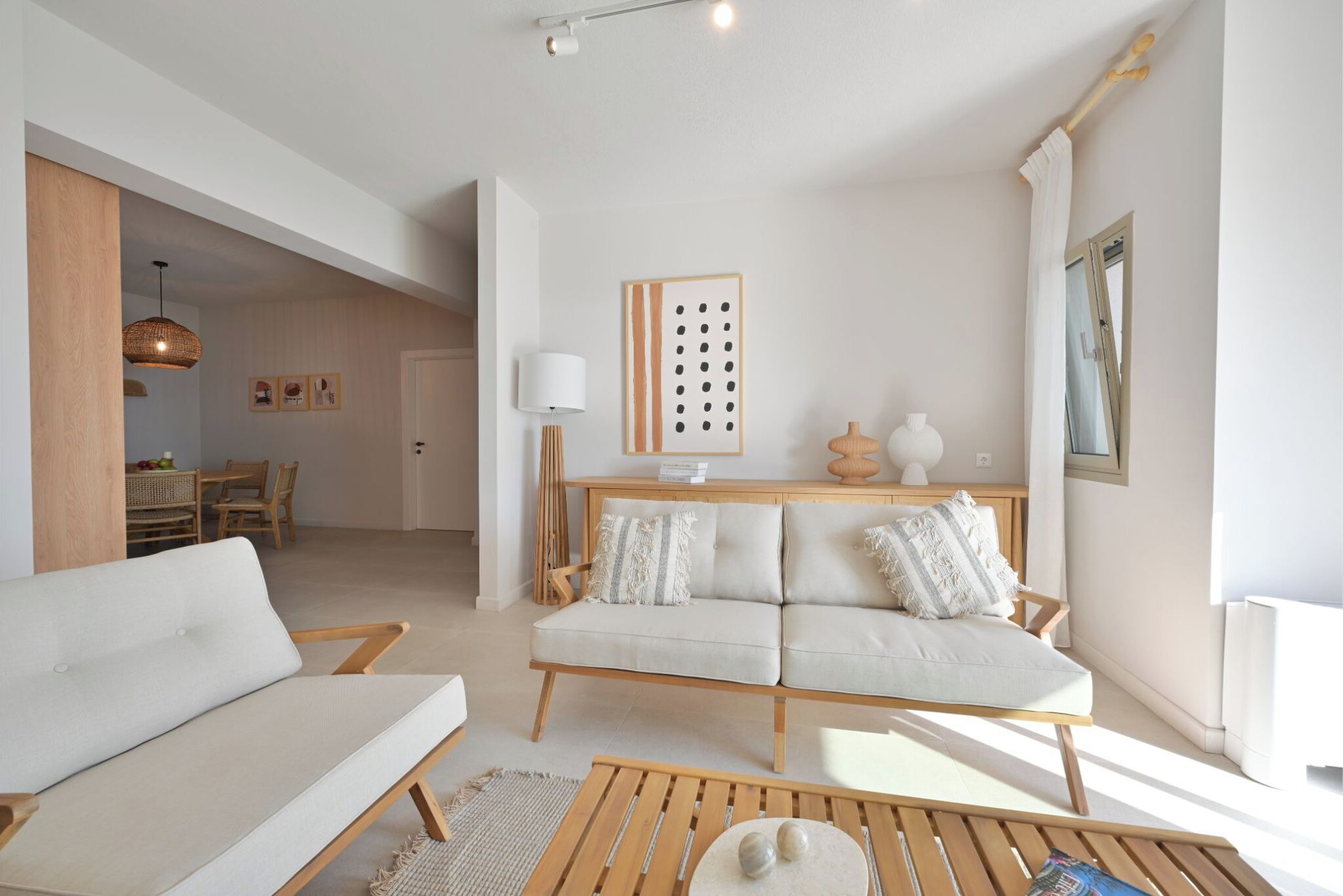 A modern living room with a sofa, coffee table, and a dining area with a table and chairs.