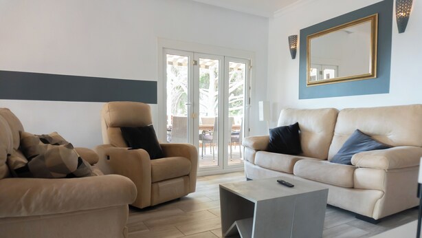 A living room with two beige sofas, a coffee table, and a large mirror on the wall. - Villa Padel (Alhaurin de la Torre)