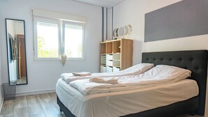 A bedroom with a large bed, a wardrobe, a mirror, and a window. - Villa Padel (Alhaurin de la Torre)