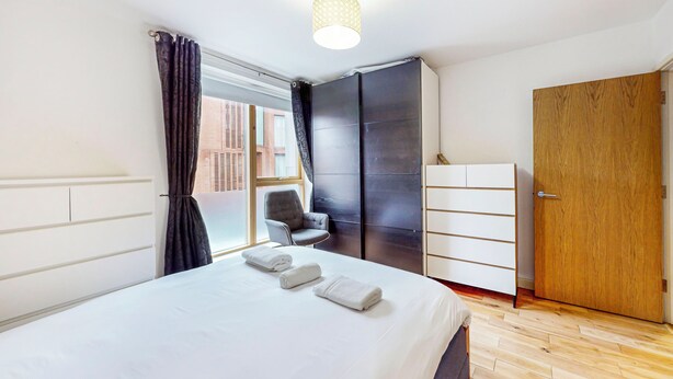 A hotel room with a bed, a chair, a wardrobe, and a window with curtains. - Modern 2Bed - 5min to Highbury & Islington Station (London)
