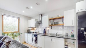 A modern kitchen with white cabinets, a stainless steel refrigerator, and a built-in oven. - Modern 2Bed - 5min to Highbury & Islington Station (London)