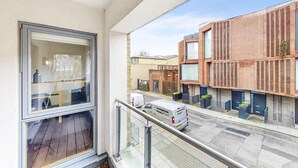 A balcony with a view of a modern building and a street with a white van. - Modern 2Bed - 5min to Highbury & Islington Station (London)