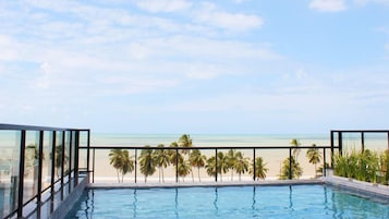 Piscina com vista para a praia e palmeiras.