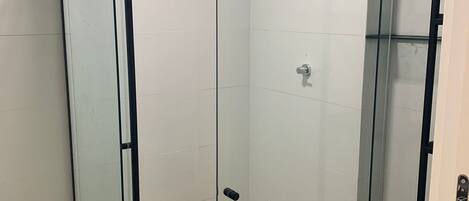 A glass-enclosed shower with a wooden floor, a visible showerhead, and a metal handle.