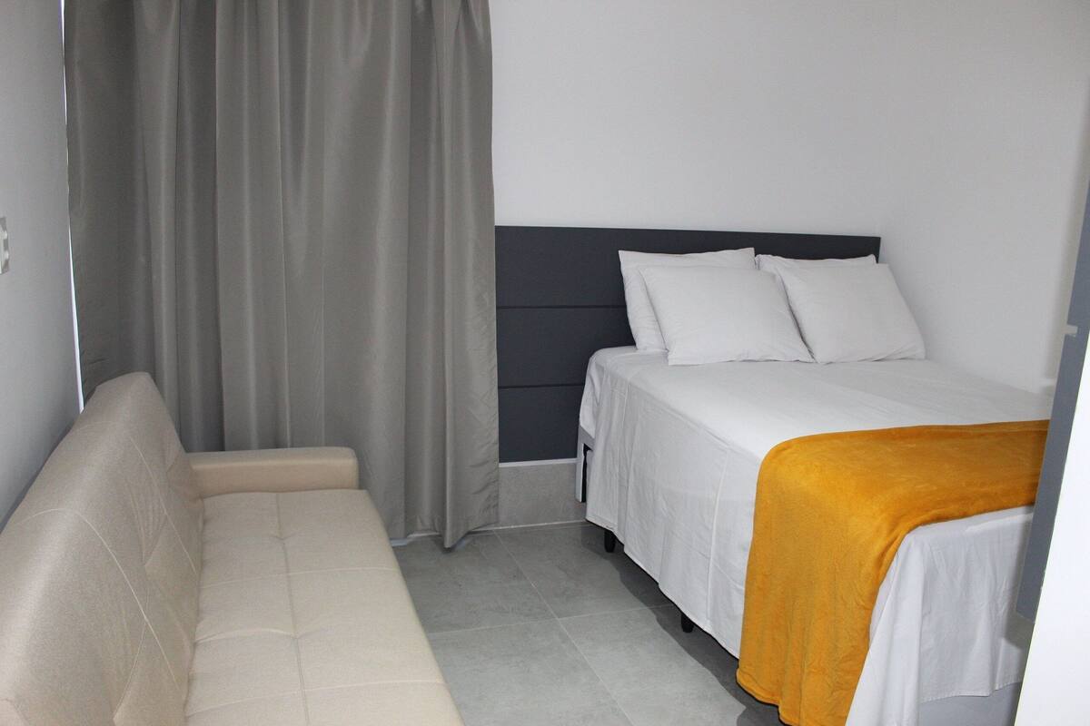 Una habitación de hotel con cama, sofá y cortina.
