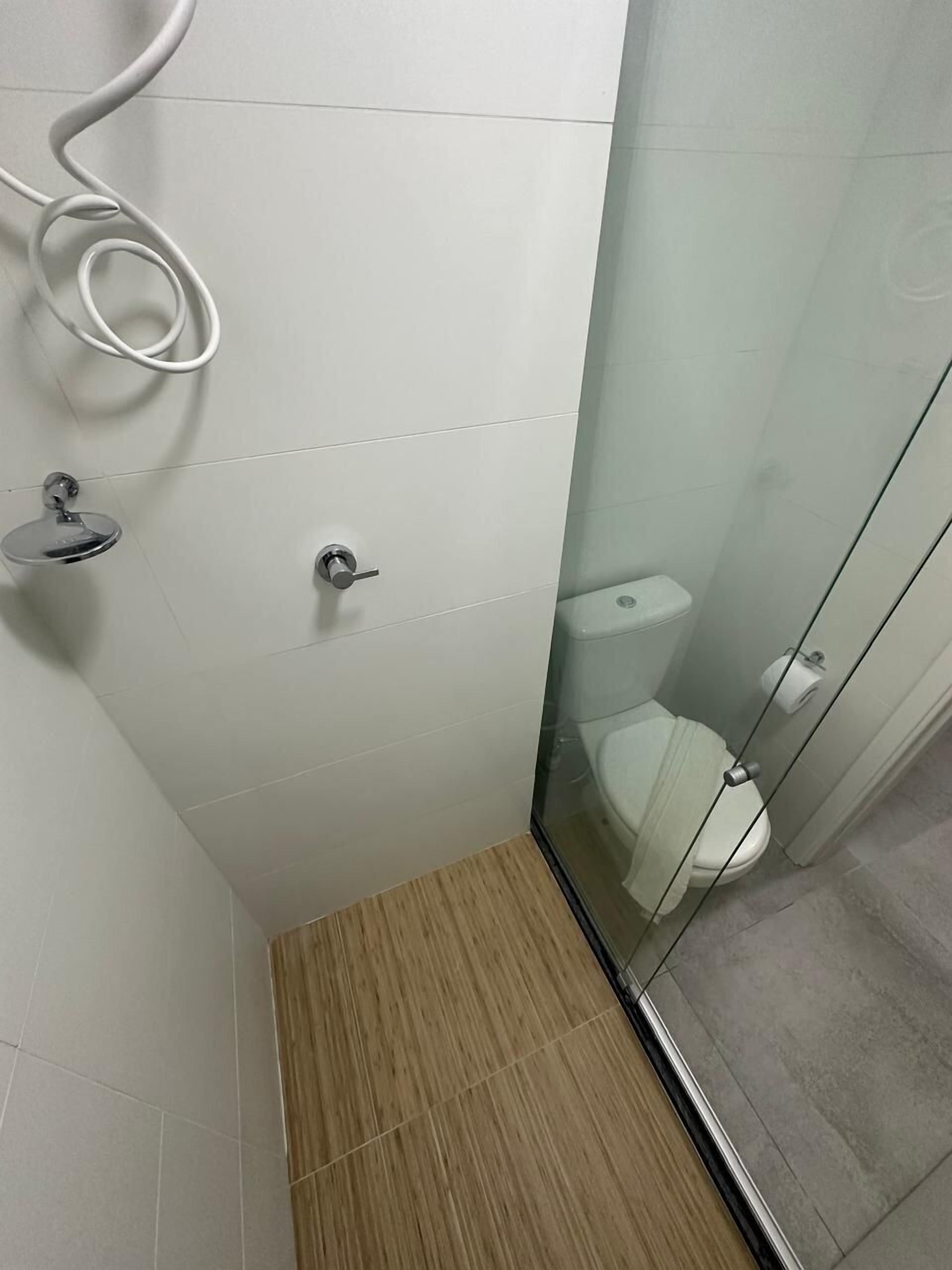 A modern bathroom with a glass shower enclosure, a toilet, and a showerhead.