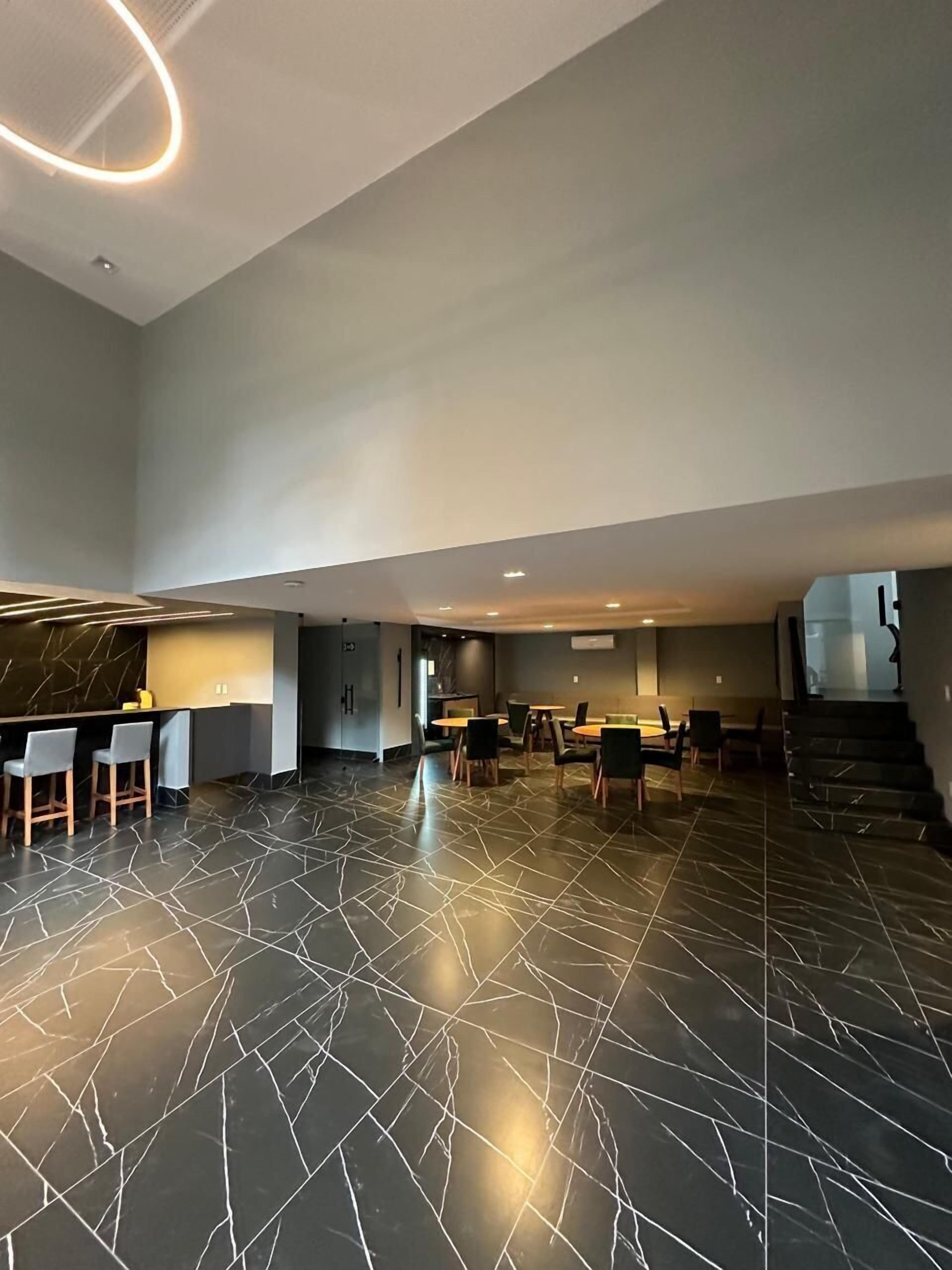 A spacious interior with a modern kitchen area, dining space, and a staircase leading to an upper level.