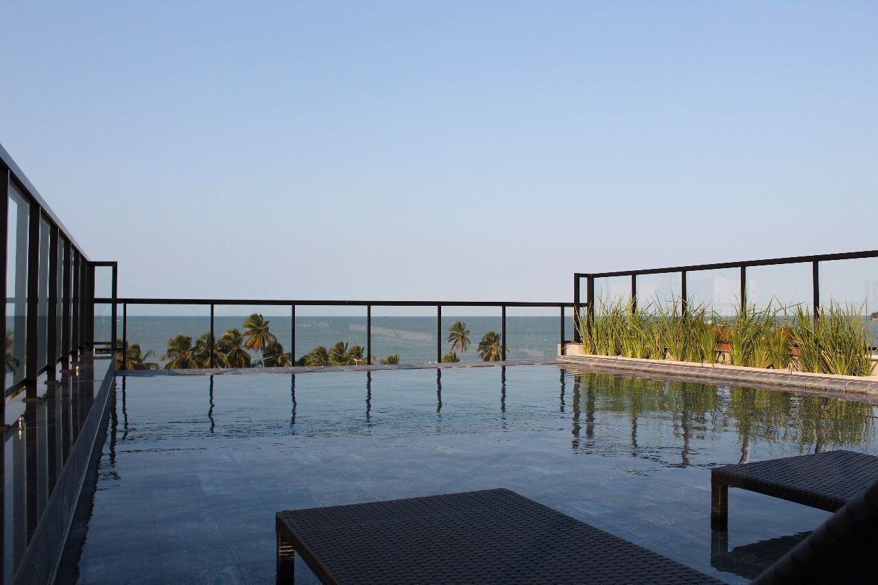 Una piscina infinita en la azotea con vistas despejadas al océano y palmeras.