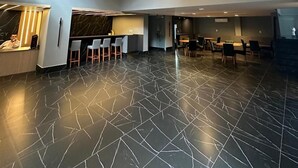 Een ruime lobby met een modern design, met een receptiebalie, een bar en een eetgedeelte met meerdere tafels en stoelen.