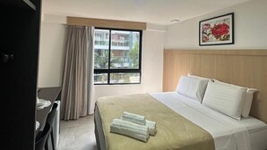 Een hotelkamer met een bed, een bureau en een raam met gordijnen.