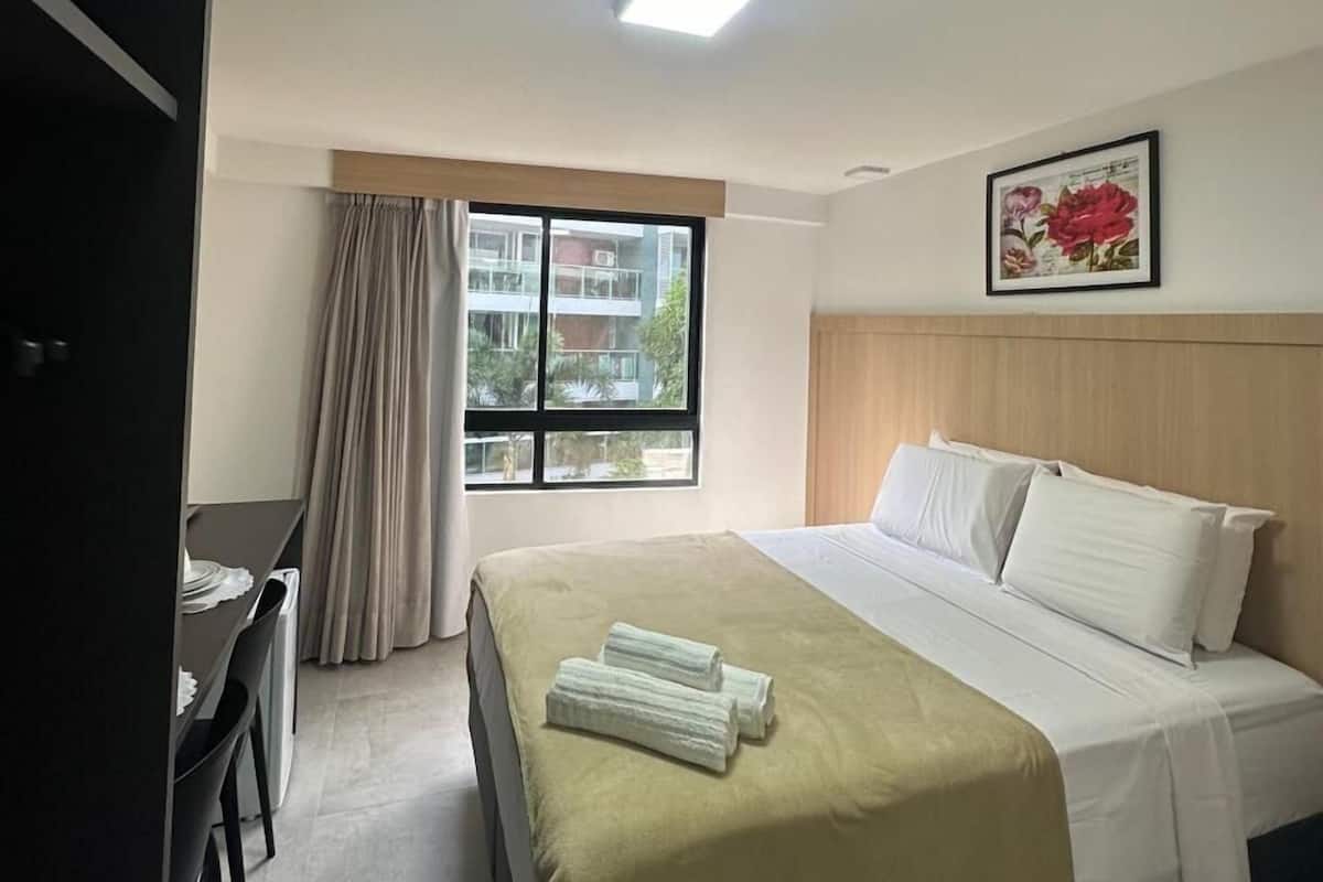 Una habitación de hotel con cama, escritorio y ventana con cortinas.