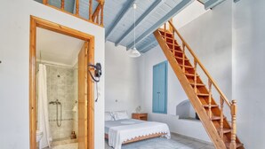 Ein Schlafzimmer mit Bett, einer Holztreppe, einer Dusche und einem Badezimmer.