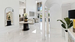 Un espace de vie spacieux et moderne, doté d’un sol en marbre, d’une table ronde et d’un grand miroir.