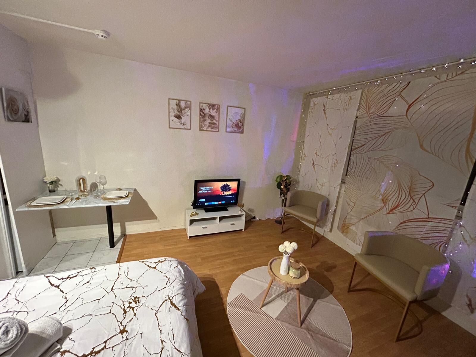 Een moderne hotelkamer met een bed, een televisie, een bureau en een zithoek.