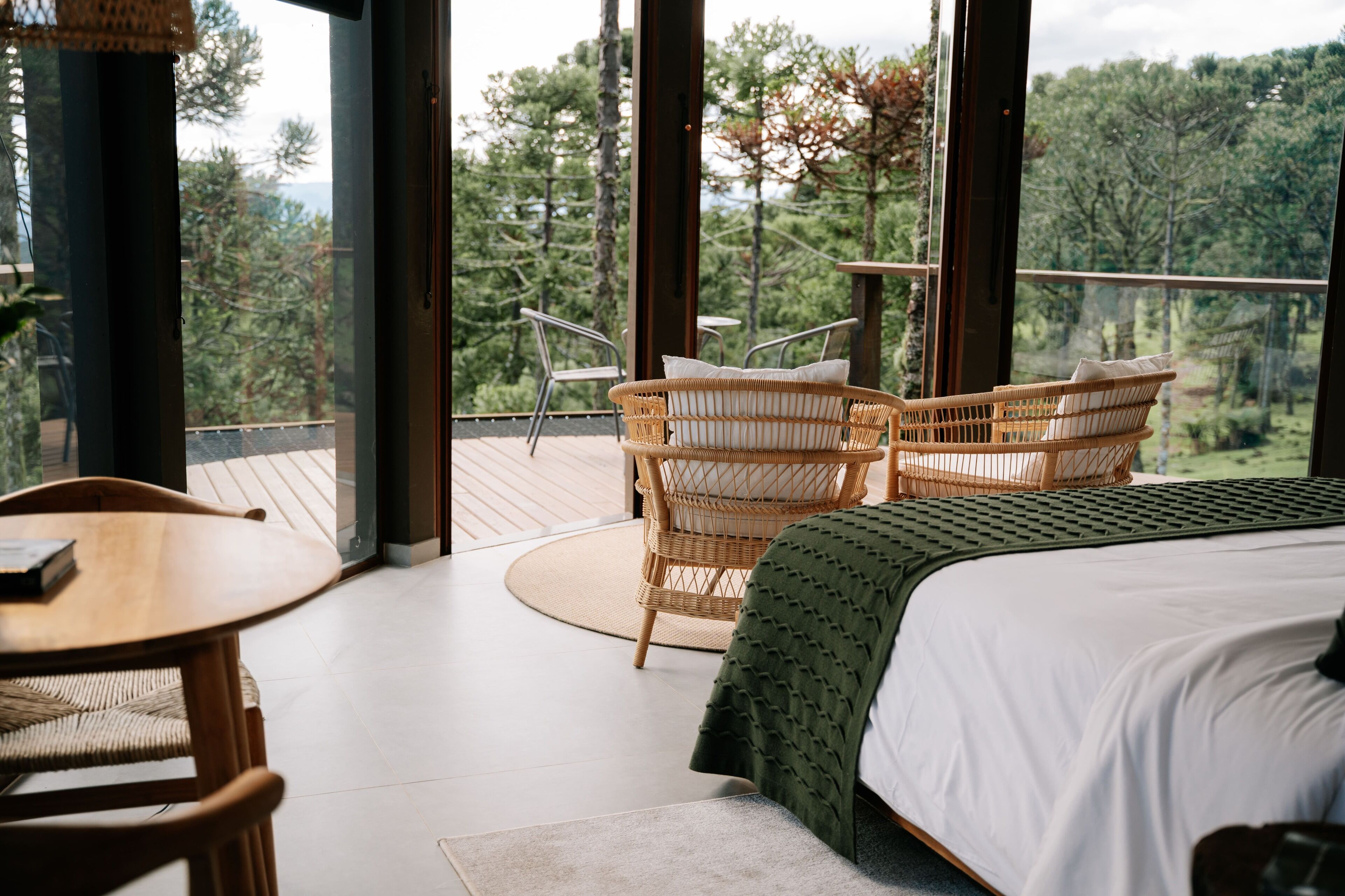 Un dormitorio con una cama grande, una mesa de madera y dos sillas de mimbre.
