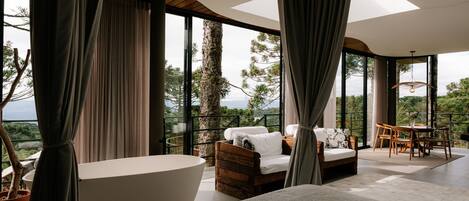 A modern bedroom with a large window, a bathtub, and a sofa.