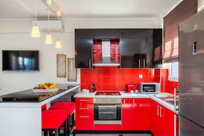 A modern kitchen with red cabinets, stainless steel appliances, and a central island with seating.