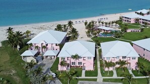 Ein Strandhotel mit mehreren rosa Gebäuden, einem Poolbereich und Blick auf den Strand.