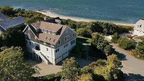 A two-story house with a large front yard, a driveway, and a view of the ocean. - Spacious 5-bedroom estate with access to private beach in peaceful Falmouth (Falmouth)