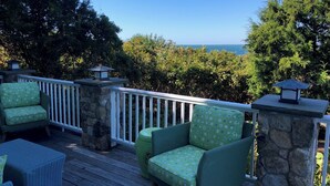 A deck with wicker furniture and stone pillars, overlooking a scenic view. - Spacious 5-bedroom estate with access to private beach in peaceful Falmouth (Falmouth)