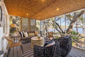 A covered outdoor seating area with a view of a lake, furnished with wicker chairs and a sofa. - Lakefront with Private Dock and Firepit (Santa Rosa Beach)