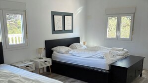 A bedroom with two beds, a ceiling fan, and two windows with blinds. - Villa with heated pool and private padel court (Pinos de Alhaurín)