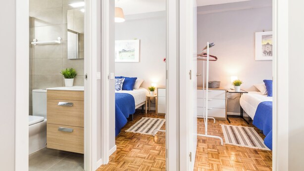 A modern bedroom with two beds, a bedside table, a small desk, and a wardrobe. - Cozy apartment close to Atocha and Retiro, Madrid - Cuore Apartments (Madrid)
