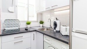 A modern kitchen with white cabinets, a black countertop, a washing machine, a toaster, and a sink. - Cozy apartment close to Atocha and Retiro, Madrid - Cuore Apartments (Madrid)