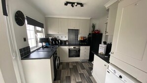 A compact kitchen with white cabinets, a black countertop, and a built-in oven. - Paddock View - Snetterton, Norfolk (Norwich)