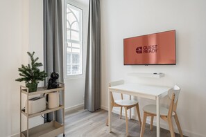 Relax in a serene space with a desk, TV, and potted plant.