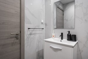 Bathroom features a sleek design with a bathtub, vanity, and towel rack.
