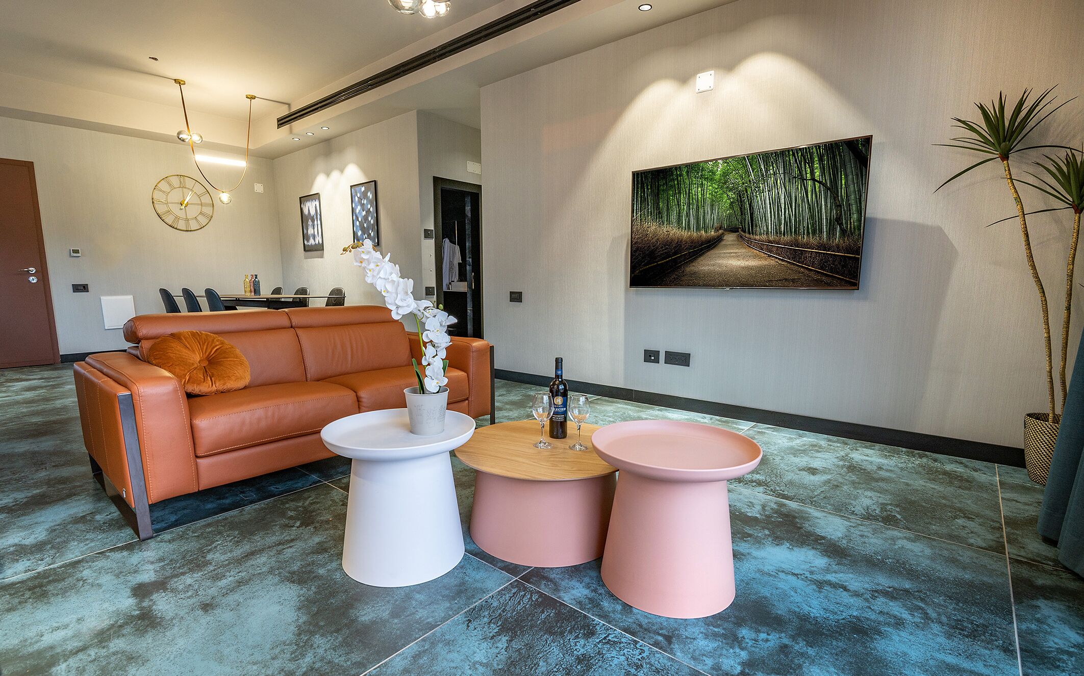 Een moderne woonkamer met een leren bank, een witte orchidee en roze bijzettafels.