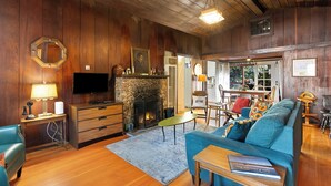 Ein gemütliches Wohnzimmer mit Holzwänden, einem Kamin, einem Fernseher und einer bequemen Sitzecke.