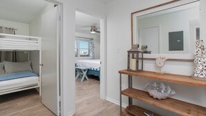 Een kamer met een stapelbed, een bureau met spiegel en een plank met decoratieve objecten.