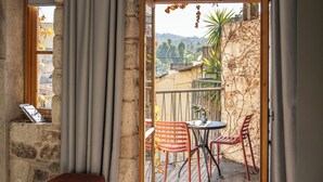 A bedroom with a bed, a window, and a view of an outdoor patio with chairs and a table. - Asomaton by Oniro (Athens)